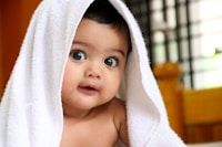 A graphic of a woman on her back with her knees towards her chest, holding a baby on her shin.